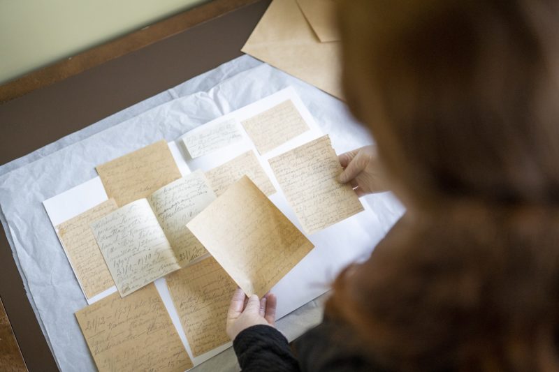 Museon työntekijä käsittelee arkiston papereita
